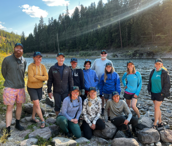 Team of people standing at edge of a river.